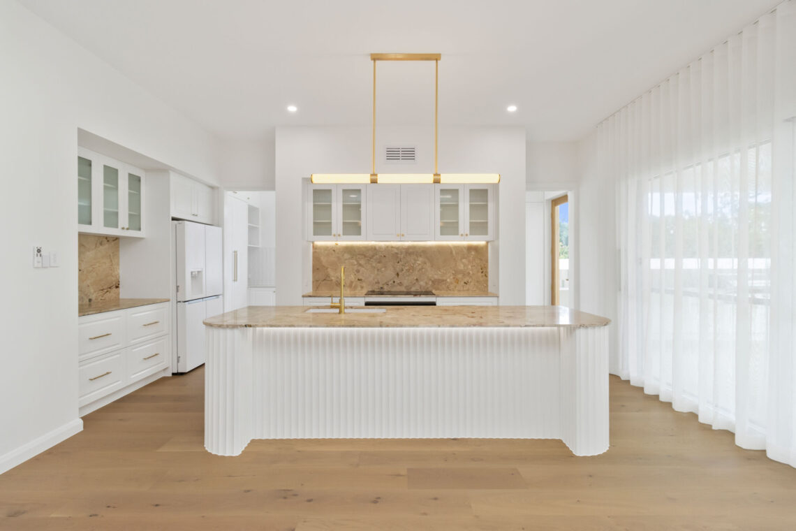 Modern kitchen with a unique stone bench and floor-to-ceiling sheer curtains